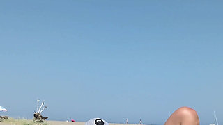 She masturbates her on the naturist beach in public with a voyeur who passes by