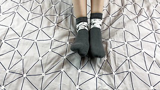 Girl with long legs caresses her feet in gray New Year socks with deer